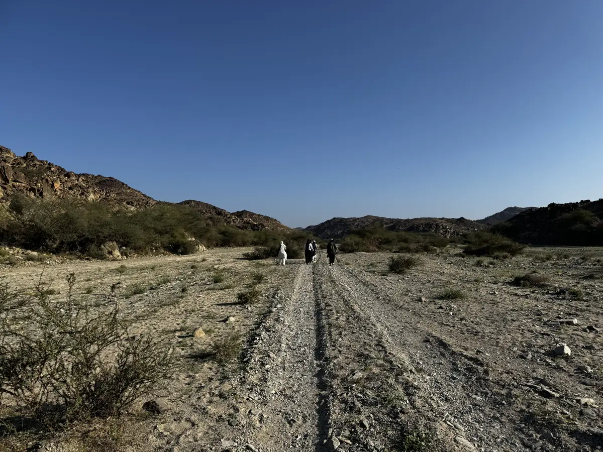 Three sisters walking a sandy track through a wadi