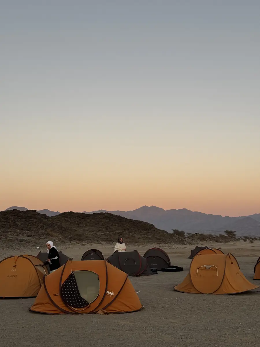 Orange pop-up tents on the sand at sunset