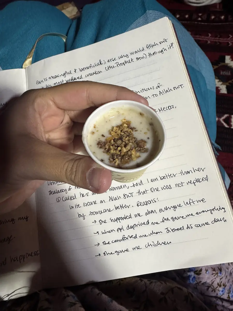 A cup of qahwa held over a handwritten journal