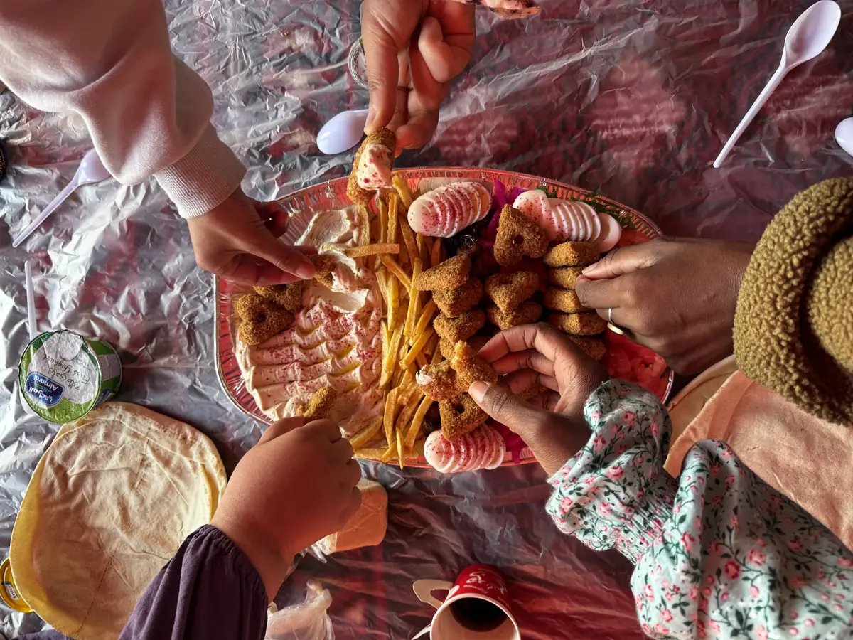 Hands reaching into a shared platter of food